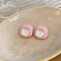 Détail de boucles d'oreilles géométriques roses avec un centre en émail blanc brillant - Rose