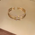 Primo piano di un bracciale a doppio strato con fiocco dorato e pavé di zirconi cubici. - Stile Fiocco / Oro
