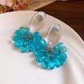 Close-up detail of blue resin flower tassel stud earrings with clear teardrop top - Blue