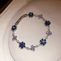 Detailopname van een zilverkleurige armband met blauwe en heldere zirkoonbloemen - Zilver-Donkerblauw-Lichtblauw