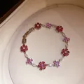 Gedetailleerde weergave van een bloemenarmband met roze en rode zirkoniasteentjes - Zilver-Rozerood-Roze