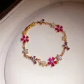 Detail van een elegante zirkonia bloemenarmband met gekleurde edelstenen goud. - Goud-Magenta-Paars