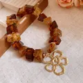 Close-up of retro amber acrylic bracelet with a gold textured flower charm - Necklace