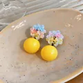 Close-up detail of stylish resin flower stud earrings featuring a vibrant yellow round sphere - Yellow