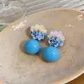 Close-up view of blue gradient flower resin earrings with large light blue spheres. - Blue