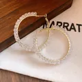 Close-up of gold hoop earrings wrapped with clear faceted glass beads on fabric. - Round / Silver Needle / White