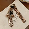 Close-up of leopard print skinny scarf with black star patchwork detail and studs. - Brown