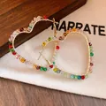 Macro shot showing colorful glass beads wrapped around golden heart hoop earrings - Heart / Silver Needle / Colorful