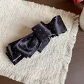 Detailed close-up of elegant black polka dot ribbon bow hair clip on a textured mat - Banana Clip (HH9722) / Black