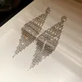 Close-up macro view of glittering rhinestone rhombus tassel drop earrings on white display - Rhombus Tassel Style / Silver