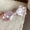 Close-up view of a pink satin polka dot bow hair clip with an elegant golden charm - Banana Clip (HH9723) / Pink