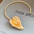 Close-up of the elegant gold calla lily pendant on a minimalist metal choker necklace - Golden Choker