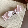 Detailed view of the pink satin polka dot bow hair clip on a textured background. - Banana Clip (HH9722) / Pink
