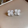 Dettaglio ravvicinato di eleganti orecchini a fiore in argento con zirconi lucenti. - Bianco