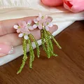 Dettaglio degli orecchini a lobo rosa a forma di fiore con delicate nappe di perline. - Rosa-Verde