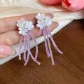 Dettaglio ravvicinato di orecchini a fiore con eleganti nappe di perline di vetro viola - Bianco-Viola