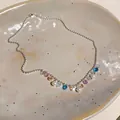 Dettaglio di una collana di perle scintillanti con gocce di gemme colorate su un piatto. - Collana della Clavicola Dopamina / 46cm / Argento - Arcobaleno