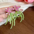 Primo piano di orecchini a fiore rosa con lunghe nappe di perline di vetro verdi. - Rosa Fragola - Verde