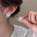 Detailed view of elegant silver hollow spiral earrings with a pearl center on ear - Hollow Spiral Pearl Stud Earrings (HE33830) / White