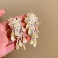 Vue détaillée des boucles d'oreilles fleurs jaunes avec glands perlés et gouttes. - Jaune