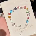 Dettaglio di un bracciale in zirconi colorati con varie pietre su un sacchetto regalo - Stile Splicing Multiforma (WB1150) / Colorato