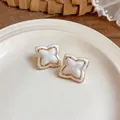Detailed view of elegant gold-rimmed clover earrings with pearlescent white petals - Beige