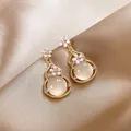 Close-up detail of pink enamel flower and gourd pendant earrings with cat's eye stone. - Silver Needle Gourd Style / Gold-Pink
