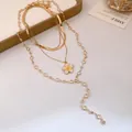 Dettaglio ravvicinato di una collana d'oro a più strati con ciondolo a fiore in smalto giallo - Stile Fiore Giallo E Bianco