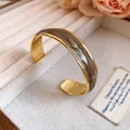 Close-up detail of 18K gold plated bangle with vintage marbled grey wave pattern. - 18K Gold Plated / White