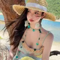 Close-up of model wearing dreamlike butterfly earrings and bead necklace at beach. - Necklace-Green
