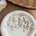 Macro detail view of elegant French style white shell bead tassel earrings on a cream plate - Hook Style / White