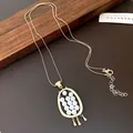Detail view of a vintage oval gold pendant necklace featuring elegant small white pearls - Gold