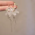Gros plan de boucles d'oreilles fleurs élégantes avec glands et finition dorée. - Or-Blanc