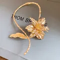 Close-up of golden metal lily flower choker with textured leaf stem detail - Choker Necklace / Gold