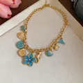 Close-up of a resort style gold chain necklace featuring blue enamel shell and seahorse pendants - Blue Floral Style / Gold