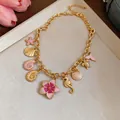 Close-up of a gold-toned necklace with colorful shell, seahorse, and flower pendants. - Pink Flower Style / Gold