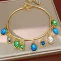 Close-up detail of a gold choker featuring colorful teardrop and oval gemstone charms - Choker-Gold-Blue-Green