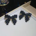 Detail view of black rhinestone pixelated bow earrings placed in a cream jewelry box - 20# Silver Needle - Gun Black