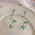 Primo piano di orecchini pendenti con fiori in acrilico e zirconi e perle verdi su piatto - Verde