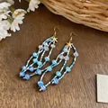 Détail des boucles d'oreilles à pampilles perlées bleues et blanches avec étoile. - Style Crochet Or-Bleu
