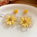Detailed macro view of yellow raffia flower earrings with hollow gold metal petals. - Yellow
