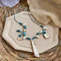 Gros plan d'un collier de perles style vacances avec coquillages, étoiles de mer et turquoise. - Collier - Doré - Bleu