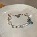 Detailed view of elegant irregular baroque pearl bracelet with a blue crystal pendant. - Silver-White