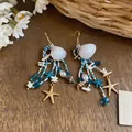 Vue détaillée de boucles d'oreilles bohèmes en perles avec coquillages et étoiles de mer - Boucles d'Oreilles Seules (Or/Bleu/Blanc)