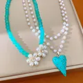 Vue détaillée d'un collier de perles fait main avec fleurs et cœur turquoise - Bleu
