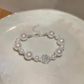 Detailed view of an elegant pearl bracelet featuring a central silver rose charm. - Silver-Pink