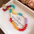 Detailed view of a vibrant rainbow acrylic beaded necklace in a white display tray. - Rose Red-Yellow-Blue-Red-Orange-Purple