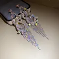 Detailed macro view of sparkling rhinestone tassel drop earrings with AB crystals. - Rainbow