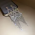 Close-up of sparkling diamond-encrusted hollow tassel drop earrings with silver needles - Silver