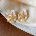 Nahaufnahme eleganter Seestern- und Muschelohrringe in Rosa und Gold-Ausführung. - Silber-Ohrstecker-Stil / Gold-Rosa